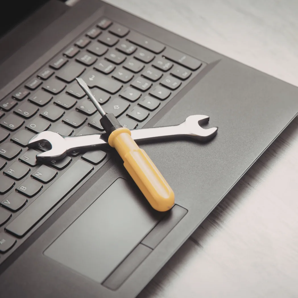 Une clé plate et un tournevis posés sur le clavier d'un ordinateur portable