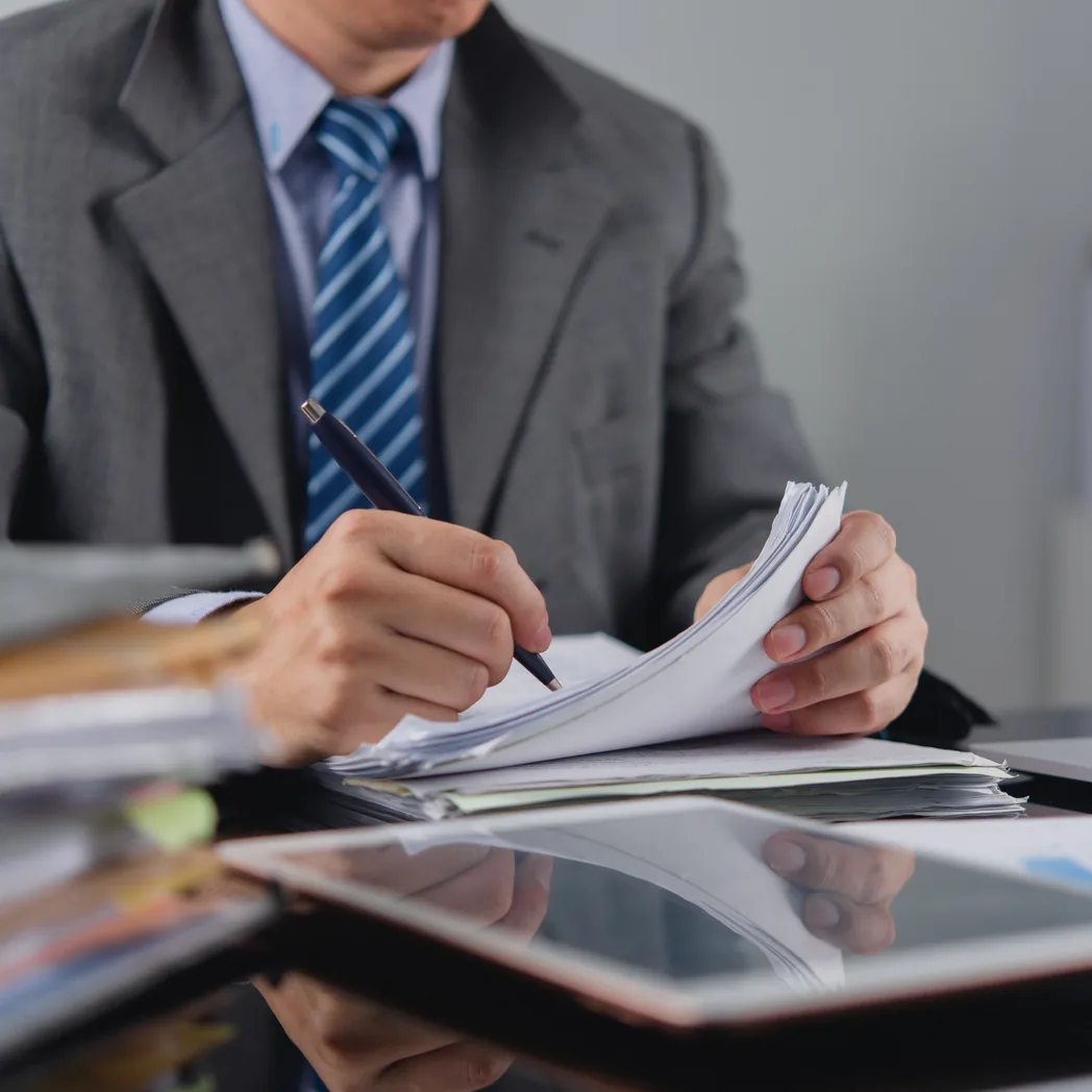 Un dirigeant annote des documents commerciaux à son bureau