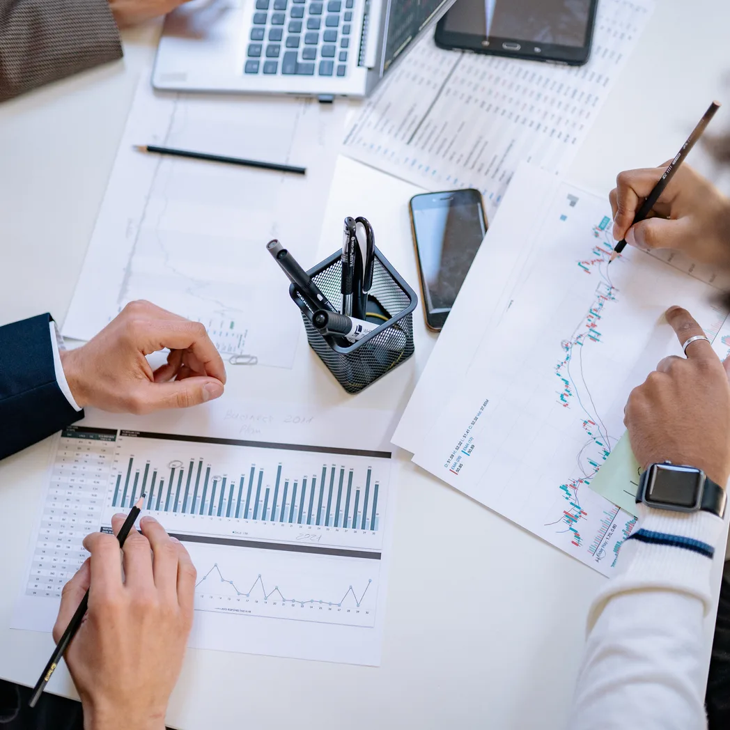 Vue de dessus d'une table de travail : graphiques commerciaux annotés, ordinateur portable et smartphones