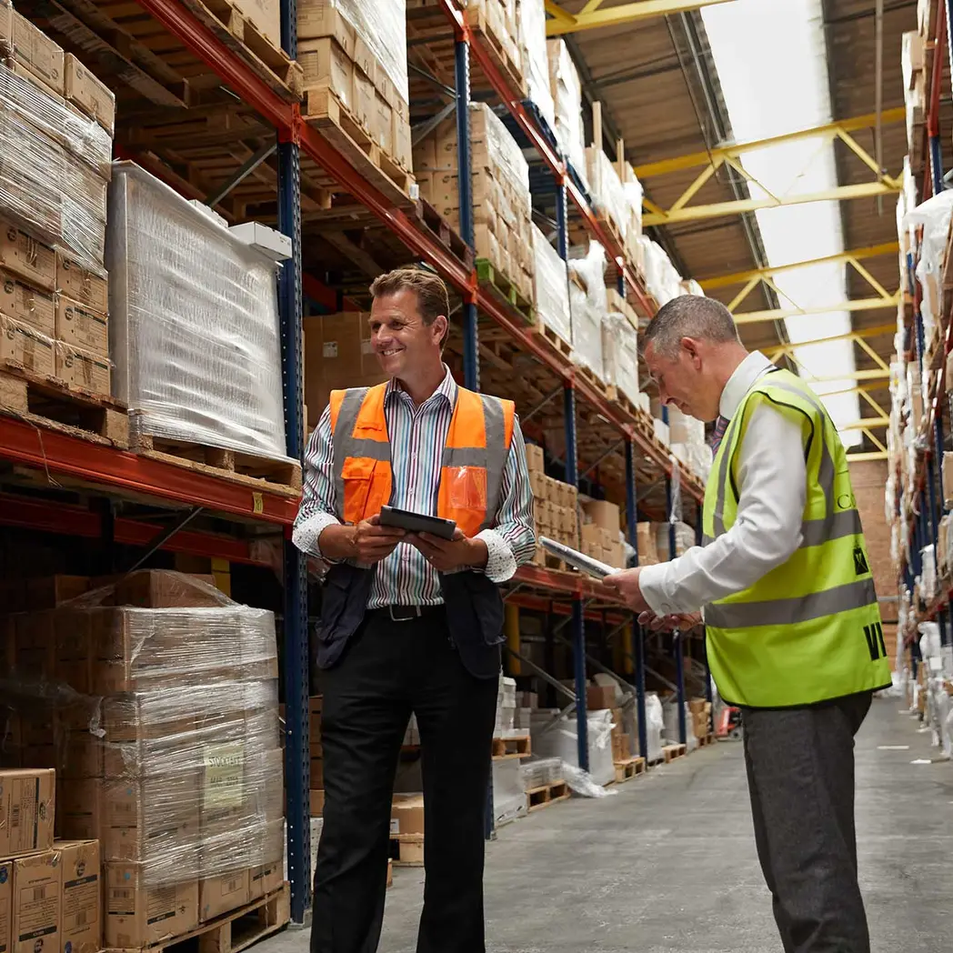 Deux responsables logistiques échangent dans un entrepôt de stockage