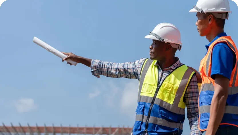 Deux conducteurs de travaux consultant un plan sur un chantier