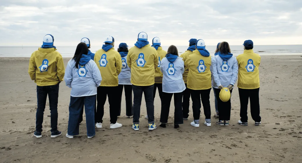 L'équipe Marcea Conseil de dos sur la plage, en vestes jaunes et blanches aux couleurs de la marque, face à la mer